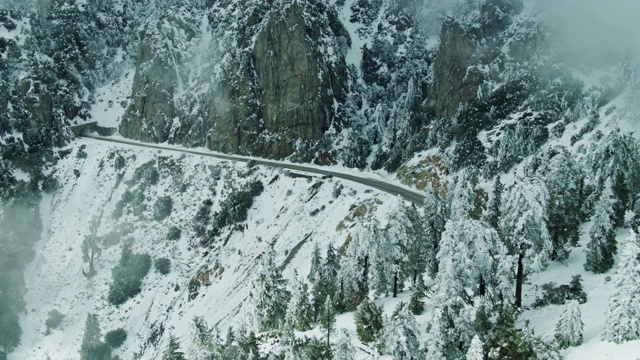 悬崖边上的隧道为洛杉矶山脊高速公路在白雪皑皑的圣加布里埃尔山-空中视频素材