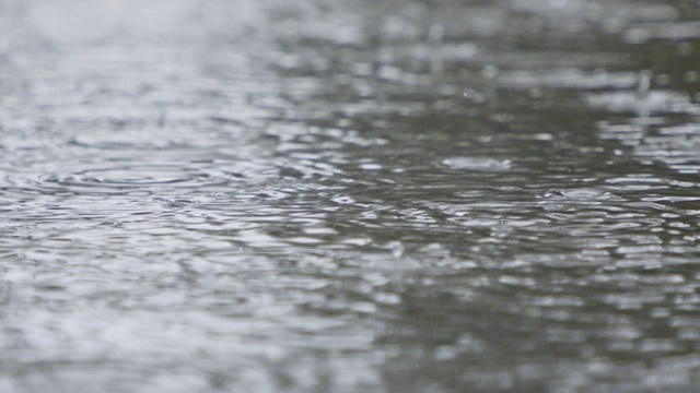 雨滴落入水坑并溅起水花的慢动作视频素材