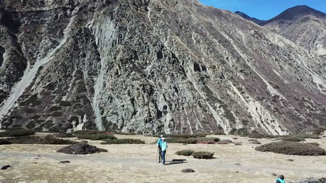 一对夫妇在尼泊尔喜马拉雅山Annapurna马戏团徒步旅行的Manang山谷，在Annapurna链和Gangapurna的景色。干燥和荒凉的景观。白雪覆盖着高耸的山峰。视频素材