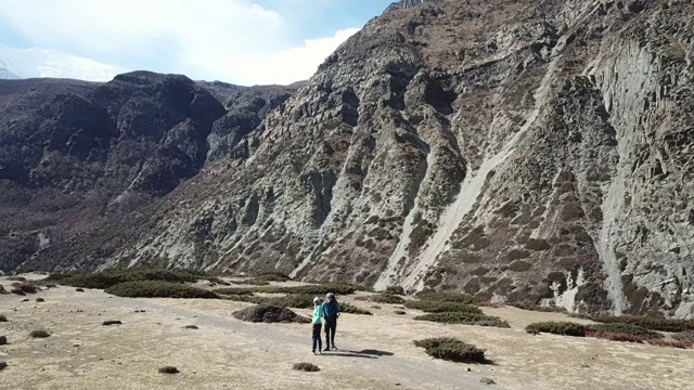 一对夫妇在尼泊尔喜马拉雅山Annapurna马戏团徒步旅行的Manang山谷，在Annapurna链和Gangapurna的景色。干燥和荒凉的景观。白雪覆盖着高耸的山峰。视频素材