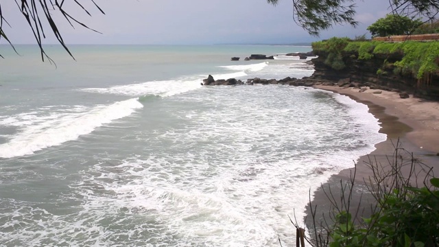 空中静态的黄昏海面，平静的波浪翻滚在岩石海岸。惊人的高悬崖之上的海洋和顶部的乌鲁瓦图寺庙。印尼巴厘岛视频下载