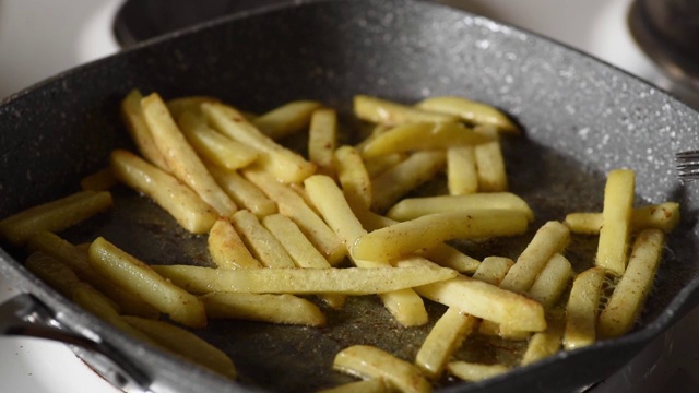 新鲜的冷冻薯条、生土豆片在热煎锅中用油准备餐与不健康的食品在家庭厨房近距离选择焦点视频素材