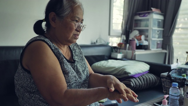 年长的亚洲妇女在家里的客厅里使用洗手液。视频素材