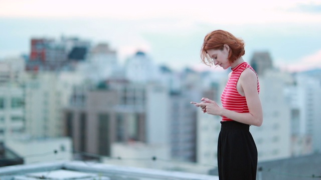 年轻女子在屋顶上用手机打字视频素材