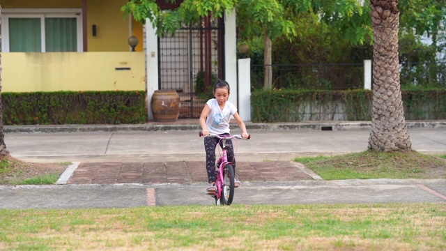 亚洲小女孩在花园里骑自行车视频素材