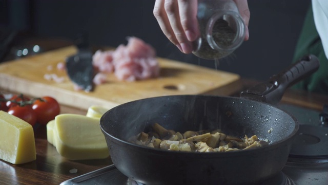 厨师将香料洒在烤蘑菇和鸡肉上。在烹饪食物。健康营养的美食厨房。做顿饭。准备吃的食物。美味的菜。做饭吃。家餐厅。视频素材