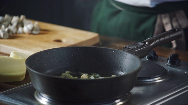 厨师将橄榄油倒入热锅中，并放入洋葱。在烹饪食物。健康营养的美食厨房。做顿饭。准备吃的食物。美味的菜。做饭吃。家餐厅。视频素材