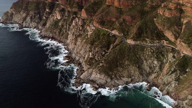 无人机俯视图拍摄的白色汽车驾驶在一个风景优美的沿海道路，无人机倾斜，同时从道路-开普敦，南非视频素材