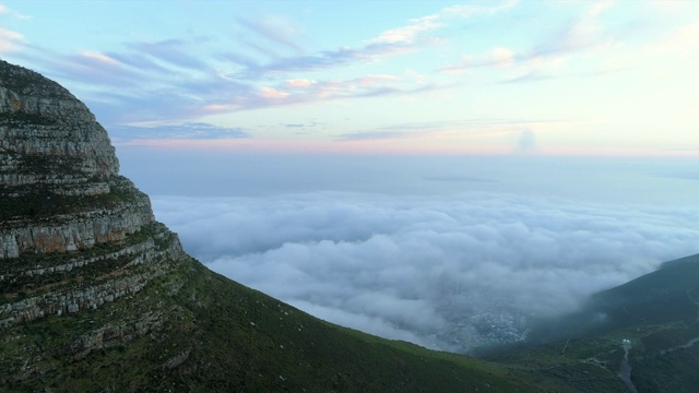 航拍一个令人惊叹的山峰在一个风景秀丽的城镇在黄昏，无人机飞向山脉穿过云层-开普敦，南非视频素材