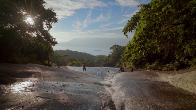 倾斜拍摄的人享受在河流对天空，朋友在森林度假- Ilhabela，巴西视频素材