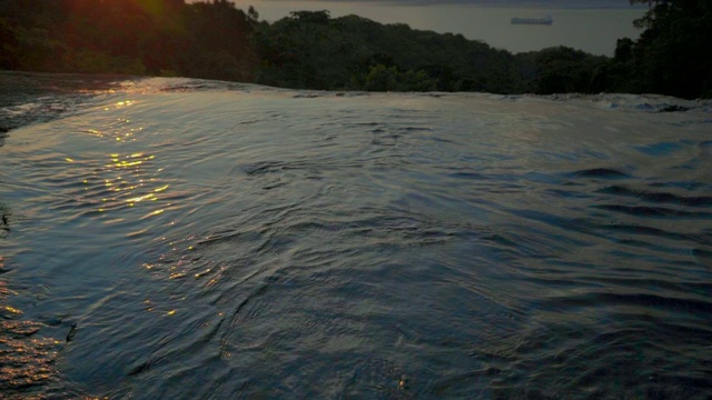 西勒运动拍摄的流动的水在岩石上对橙色的天空，河流在森林日落- Ilhabela，巴西视频素材