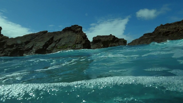 在阳光明媚的日子里，海浪拍打在海洋中的岩石悬崖上-葡萄牙亚速尔群岛视频素材