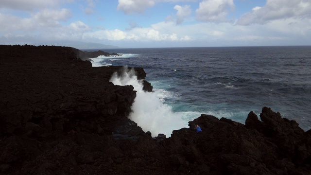 高角度的波浪溅在岩石的海岸线在大海对天空，人在海滩-亚速尔群岛，葡萄牙视频素材