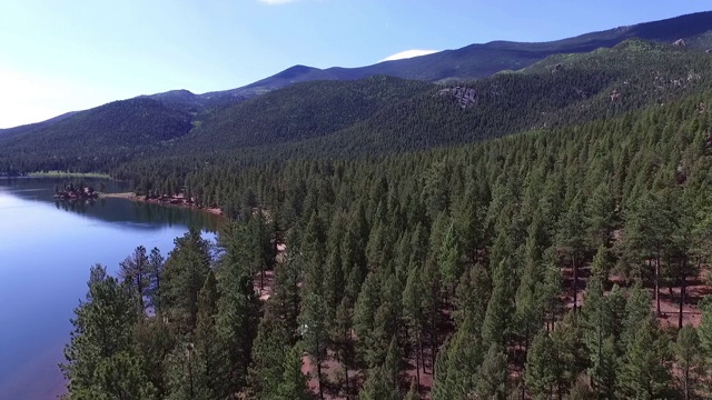 鸟瞰图的绿树在晴朗的一天平静的湖，风景的山对天空而无人机前进-湖惠灵顿，科罗拉多州视频素材