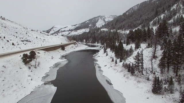 鸟瞰图上的冰原在道路和树木与雪，公路上的车辆与山脉的天空-杰克逊，怀俄明州视频素材