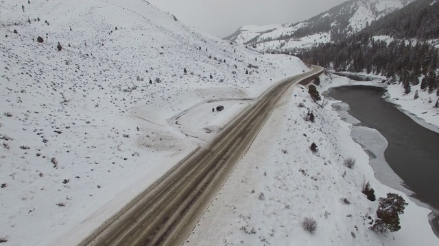 鸟瞰图，人们站在货车旁边，在积雪和河流的路边，无人机向前移动，白色的风景与山脉-杰克逊，怀俄明州视频素材