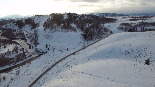 鸟瞰图上的汽车在公路上积雪覆盖的景观，森林在冬季对天空-杰克逊，怀俄明州视频素材