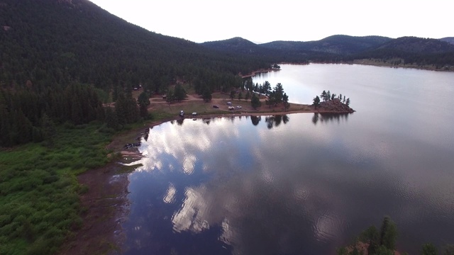 鸟瞰图反射的云彩在湖附近的森林对天空，风景的绿树在湖边与山-湖惠灵顿，科罗拉多州视频素材