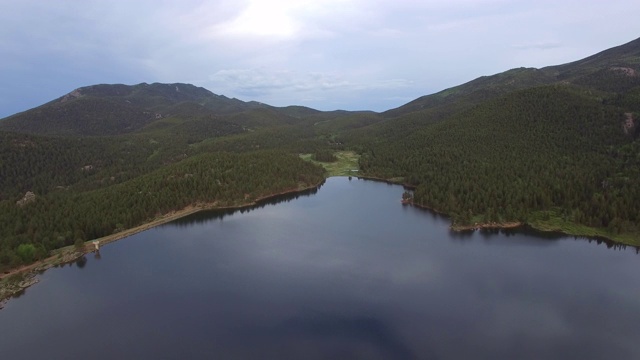 空中拍摄美丽的平静的湖在森林中对天空，无人机向前移动在田园诗般的山脉对天空-惠灵顿湖，科罗拉多州视频素材