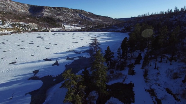 鸟瞰图上的树在雪山对天空，无人机倾斜下来在白色的冬季景观- Raton，新墨西哥视频素材