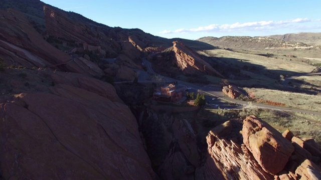 鸟瞰图的建筑通过道路和岩石山，无人机前进的高速公路悬崖在阳光明媚的一天-红石，科罗拉多州视频素材