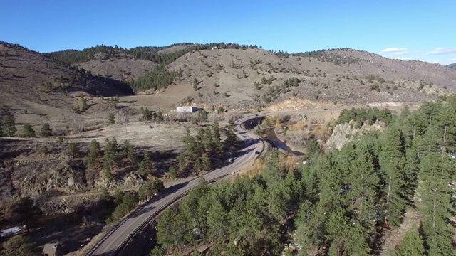 鸟瞰公路上的车辆在树林中在阳光明媚的一天，无人机向前移动的道路-红石，科罗拉多州视频素材