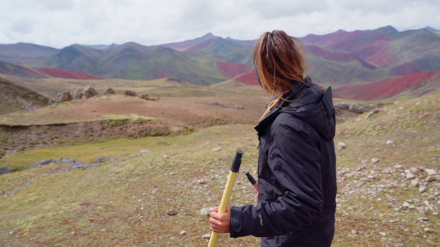 慢动作微笑的年轻游客与徒步旅行的杆子，妇女徒步对着美丽的山-彩虹山，秘鲁视频素材