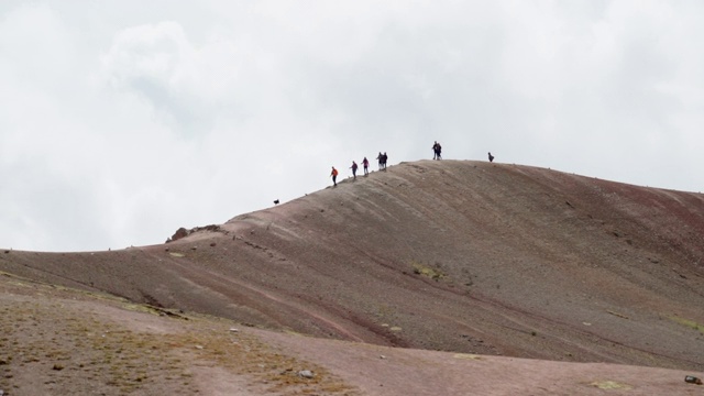 游客带着狗在山顶徒步旅行的慢镜头，在阳光明媚的日子里，低角度观看人们在天空中行走——彩虹山，秘鲁视频素材