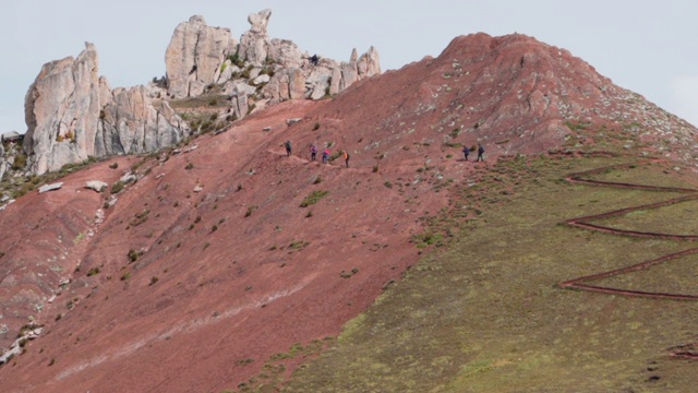 秘鲁，彩虹山，游客背对天空爬山的慢镜头，人们在岩石附近行走视频素材