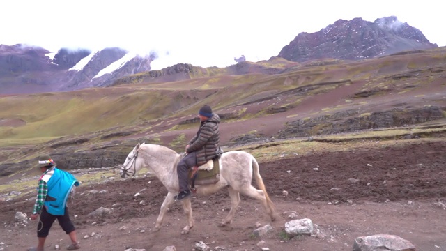 照片中，人们骑着马在山间小路上散步，秘鲁的彩虹山风景如画视频素材