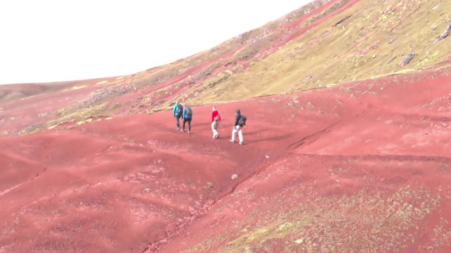 在阳光明媚的日子里，游客在岩石山上徒步旅行的慢镜头，与人一起观赏风景——彩虹山，秘鲁视频素材