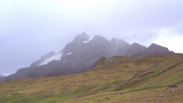 在多云的天空下，雾覆盖着岩石山脉，这是冬季田园般的风景——彩虹山，秘鲁视频素材