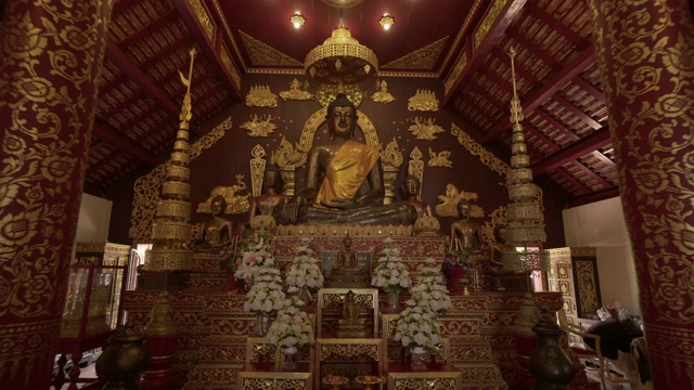 泰国清莱寺，在石柱中间的祭坛上，有发光的佛像和鲜花视频素材