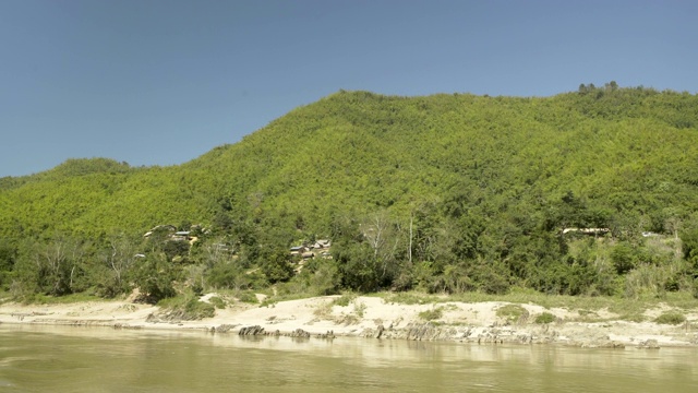 在泰国清莱，阳光明媚的日子里，用摇盘拍摄河流对着树木覆盖的山脉视频素材