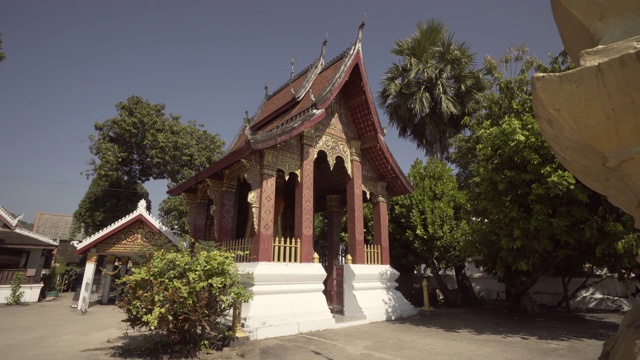 老挝琅勃拉邦，一个阳光明媚的日子，寺庙里的树木拍摄佛教建筑视频素材