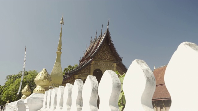 阳光明媚的一天，老挝琅勃拉邦，白色围墙映衬着天空的寺庙建筑视频素材