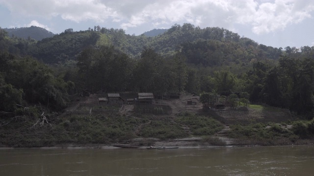 老挝，琅勃拉邦，在河边的山旁的树木旁拍摄建筑视频素材