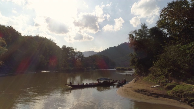 空中拍摄的游客在河上的船中树木对天空，风景的山在阳光明媚的一天-湄公河，老挝视频素材