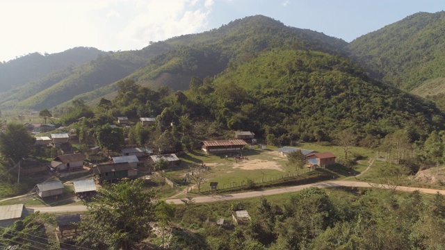 空中拍摄的房子在村庄的绿色山脉，无人机飞过山谷在阳光明媚的一天-湄公河，老挝视频素材