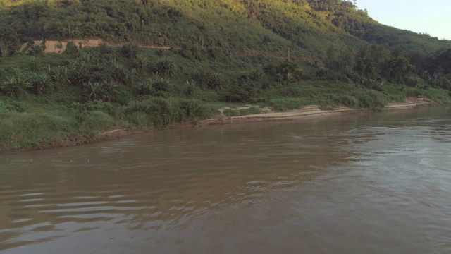 空中拍摄的河流在森林里的绿树，无人机在日落时向后飞行-湄公河，老挝视频素材