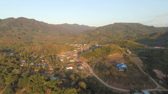 空中拍摄的房子在树木中的村庄附近的河流，以天空为背景，无人机向前飞行的住宅结构周围的山区-湄公河，老挝视频素材