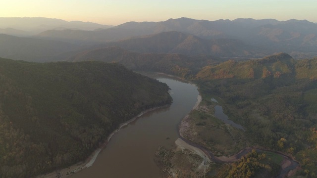 空中拍摄的河流在森林和山脉对天空，无人机在日落时飞过树木-湄公河，老挝视频素材