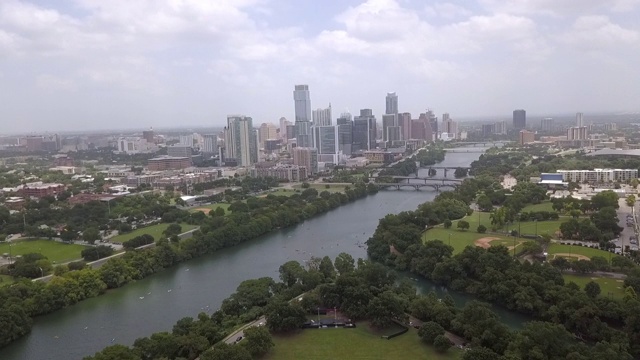 空中拍摄的河流中树木对天空，无人机上升的公园对摩天大楼在市中心-奥斯汀，德克萨斯州视频素材