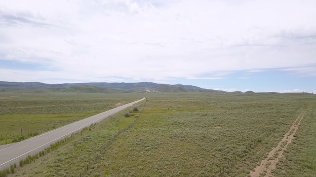 空中平移拍摄的卡车在乡村道路上移动对多云的天空，无人机飞过绿色的景观-博伊西，爱达荷州视频素材