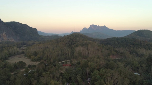 航拍的道路通过绿树在日落，无人机向前飞行的景观对天空-湄公河，老挝视频素材