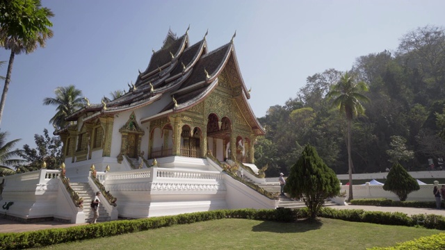 在阳光明媚的日子里，女性游客从Phra Bang走过，在城市里的植物和树木映衬下，老挝的Luang Phabang视频素材