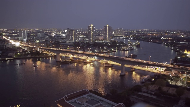 在曼谷，泰国，在夜晚的天空下，现代城市的建筑物照亮了河上的桥梁视频素材