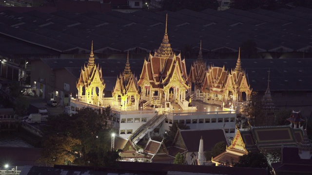 空中封锁拍摄的灯火通明的佛教寺庙在夜间的城市建筑-曼谷，泰国视频素材