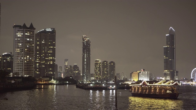 泰国曼谷，夜晚，天空下灯火通明的摩天大楼附近，河里的船只被封锁视频素材