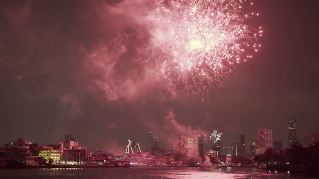 泰国曼谷，夜晚，天空与河边的建筑物映衬下，烟花在城市上空爆炸视频素材